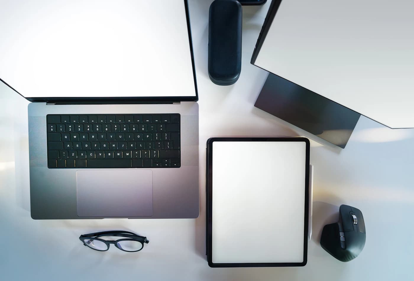 Laptop, tablet and office peripherals arranged on a bright desk — illustrative product-category photograph
