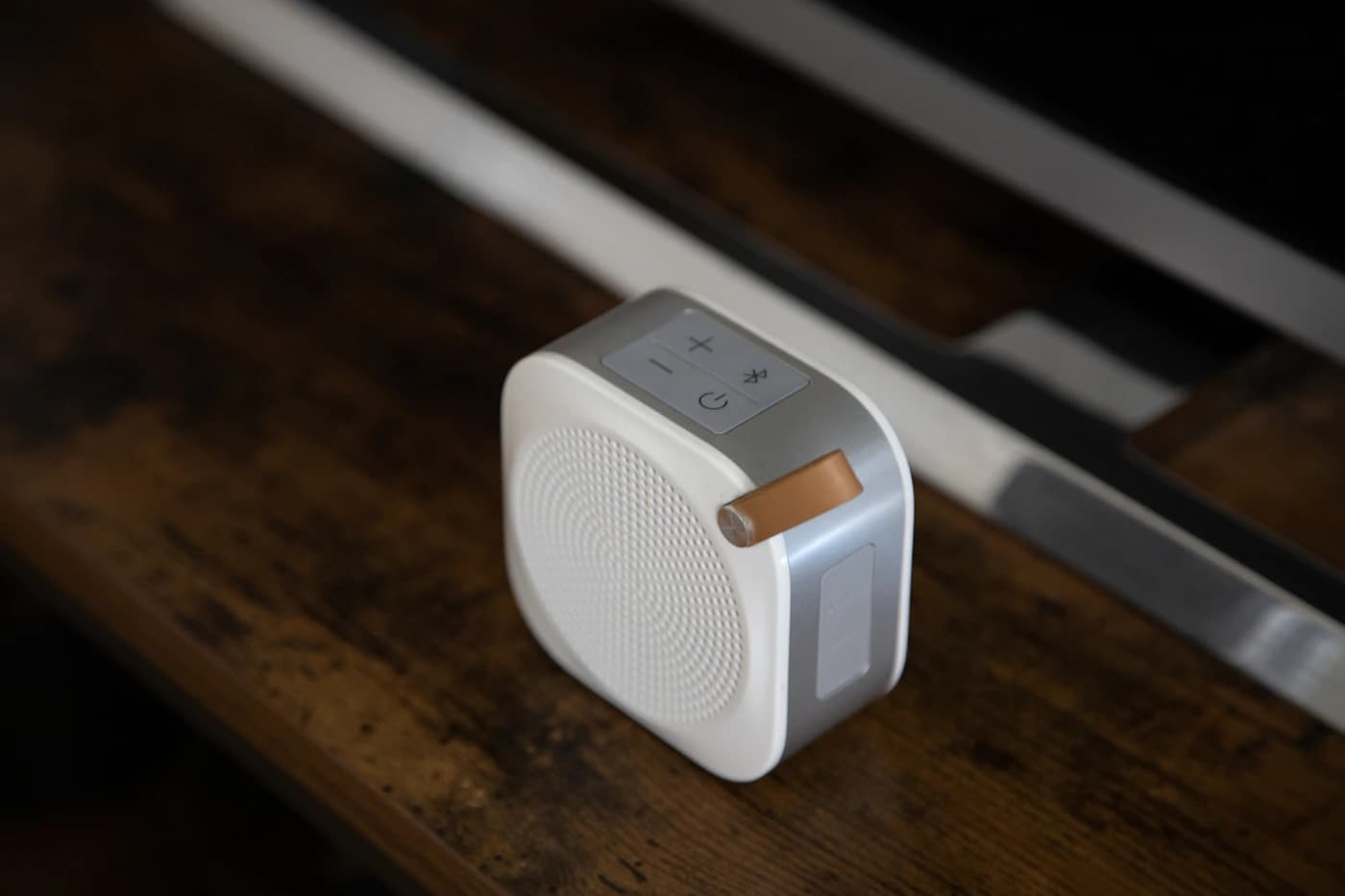 White portable speaker on a wooden table — illustrative audio and smart-home photograph